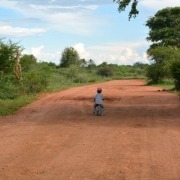 child riding bike on red dirt road, travel with kids, Puky Laufrad